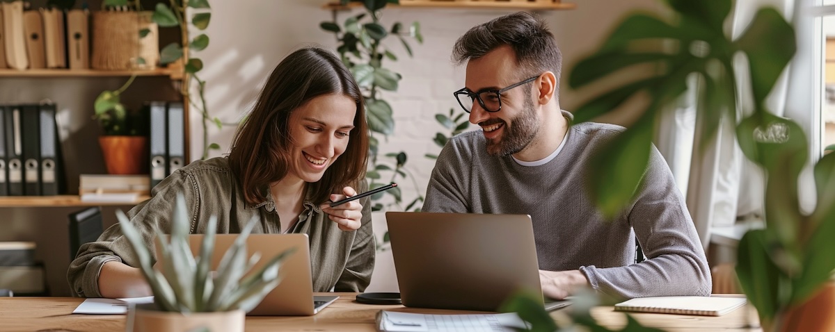 Zwei erwachsene Anfänger lernen gemeinsam eine neue Sprache am Laptop mit Notizbuch